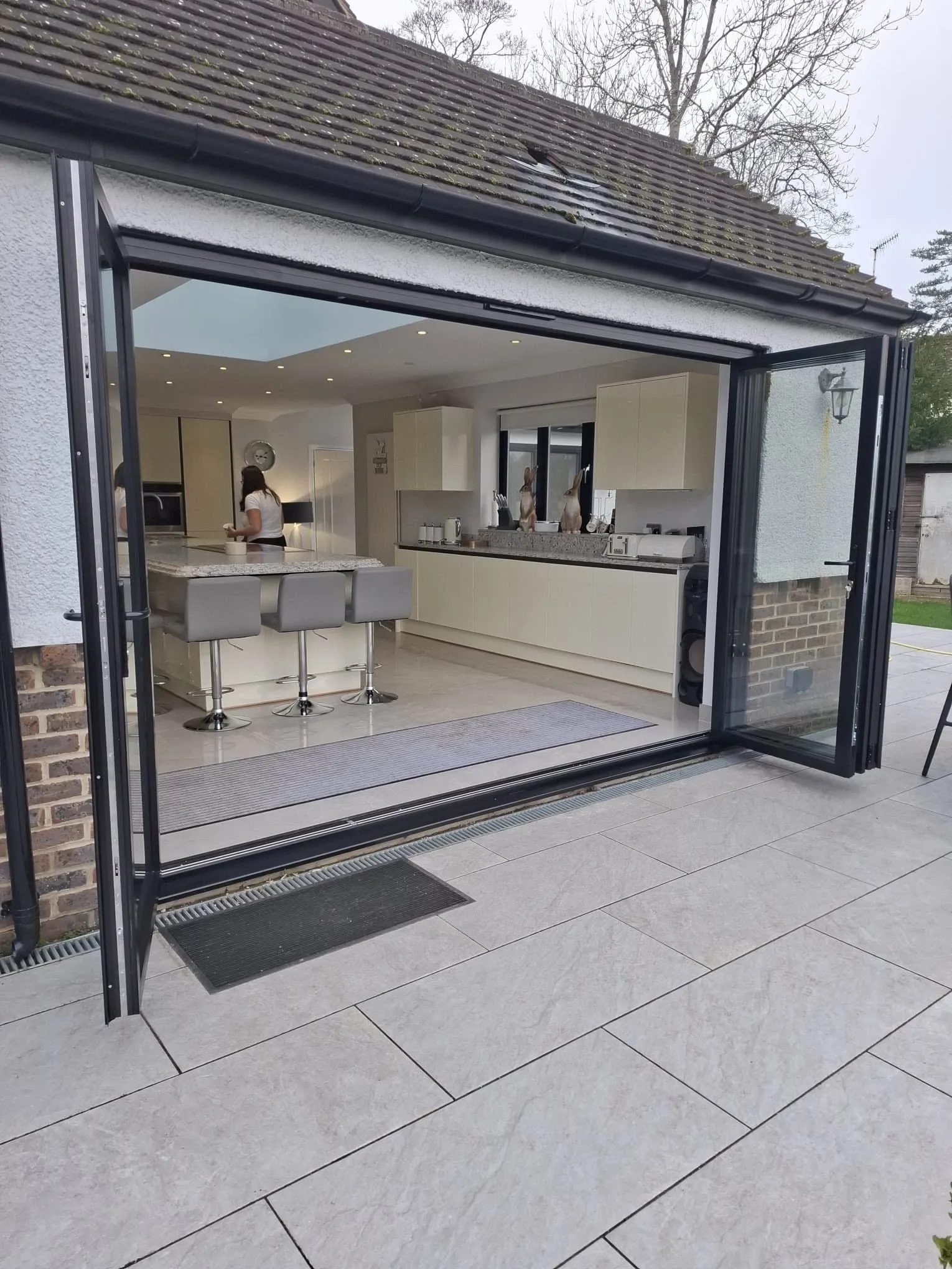 Anthracite aluminium bifold doors folded open onto a kitchen and patio