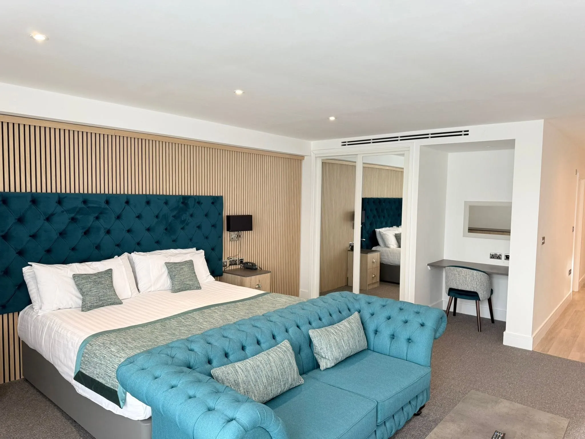 The same suite from another angle, showing mirrored wardrobes and a built-in desk