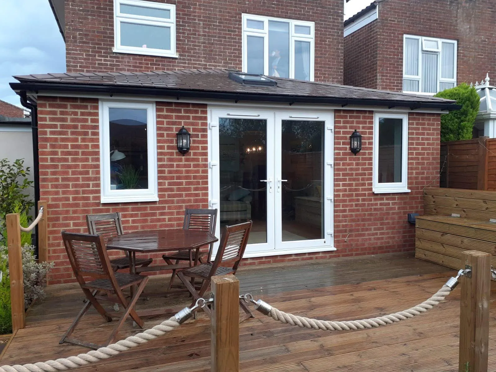 Brick extension with a tiled roof, white French doors and windows, opening onto decking