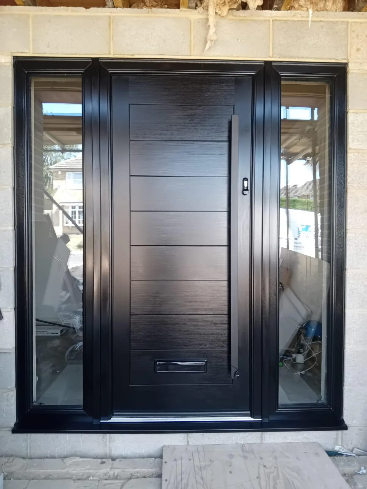 Contemporary anthracite composite front door with a long glazed panel and matching side screen