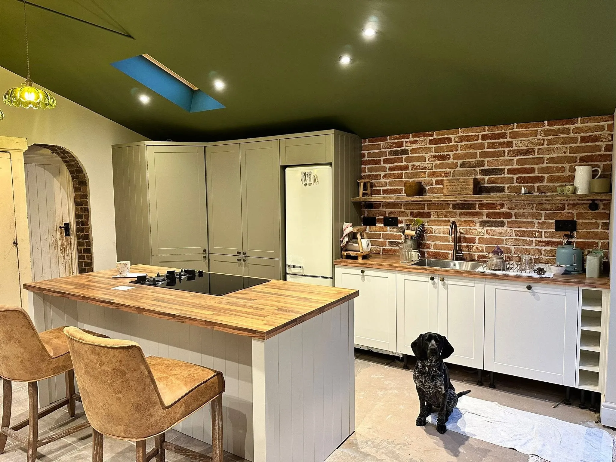 Newly installed shaker kitchen with an island, oak worktops and exposed brick wall