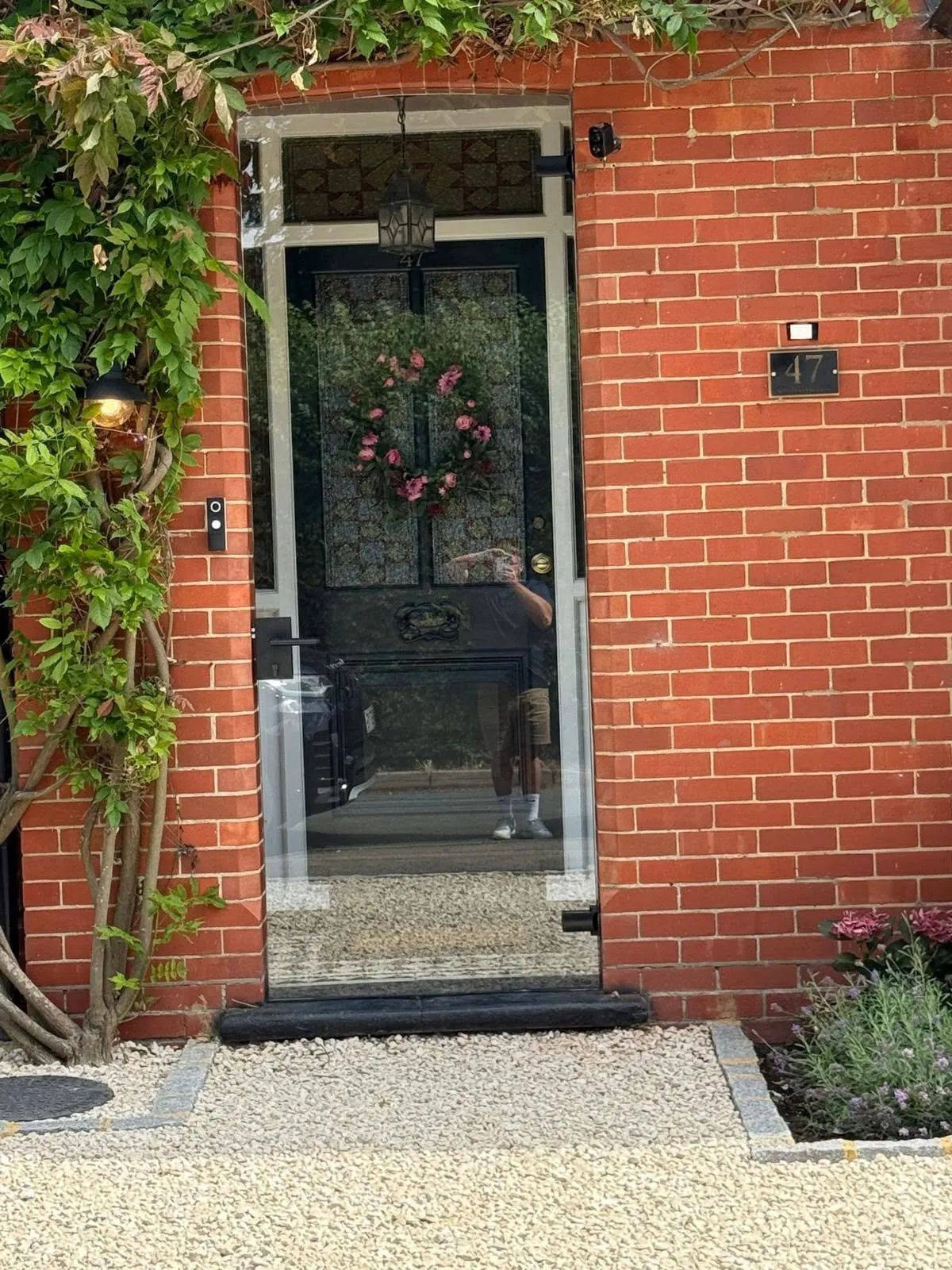 Dark back door set into a brick porch with a climbing plant around it