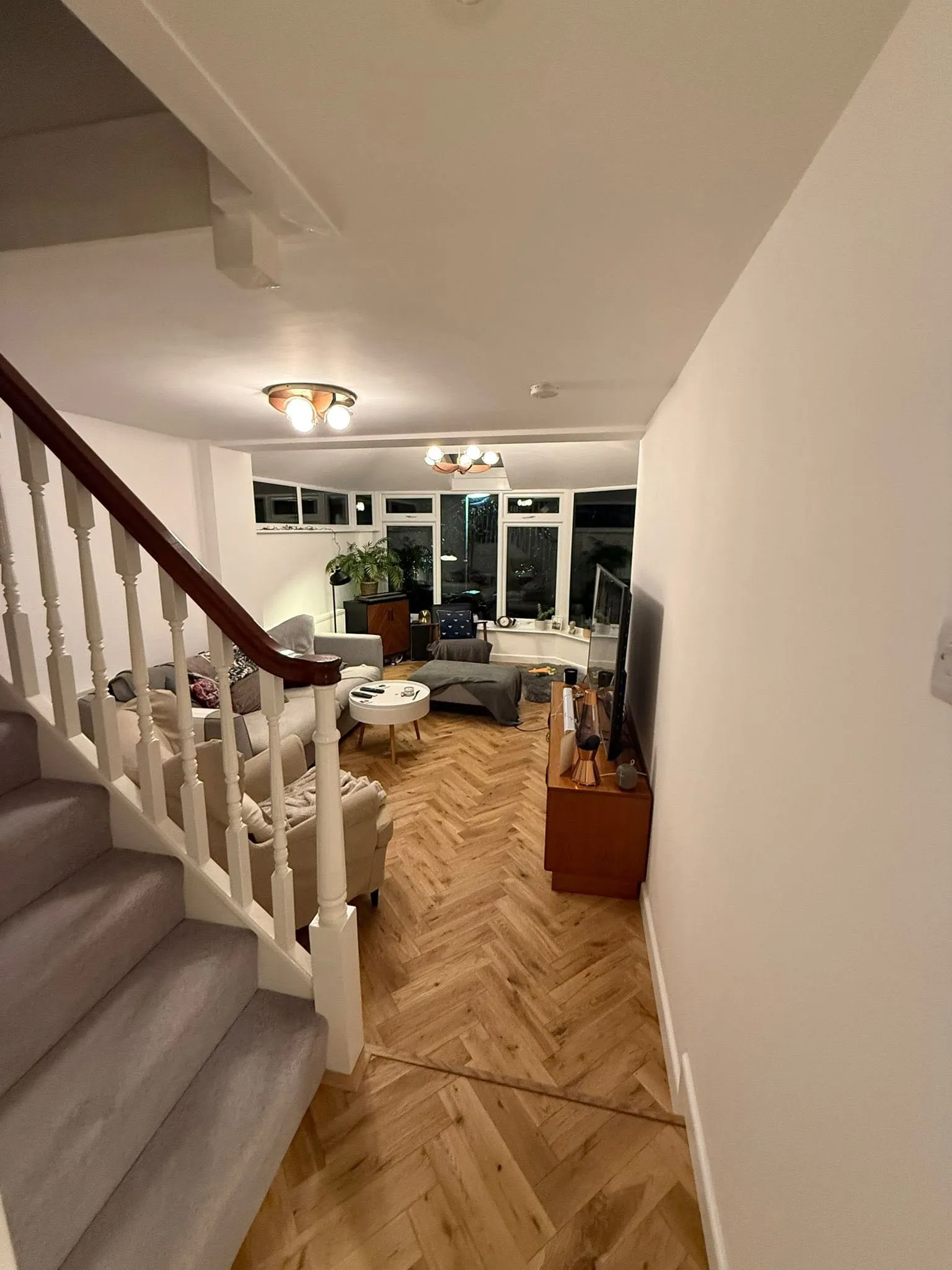 Hallway and living room with new herringbone flooring, looking through to the bay window