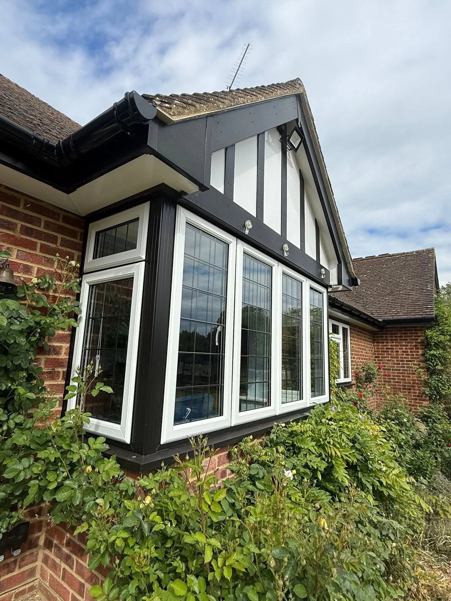 Replacement white leaded bay window set against black cladding and fascias
