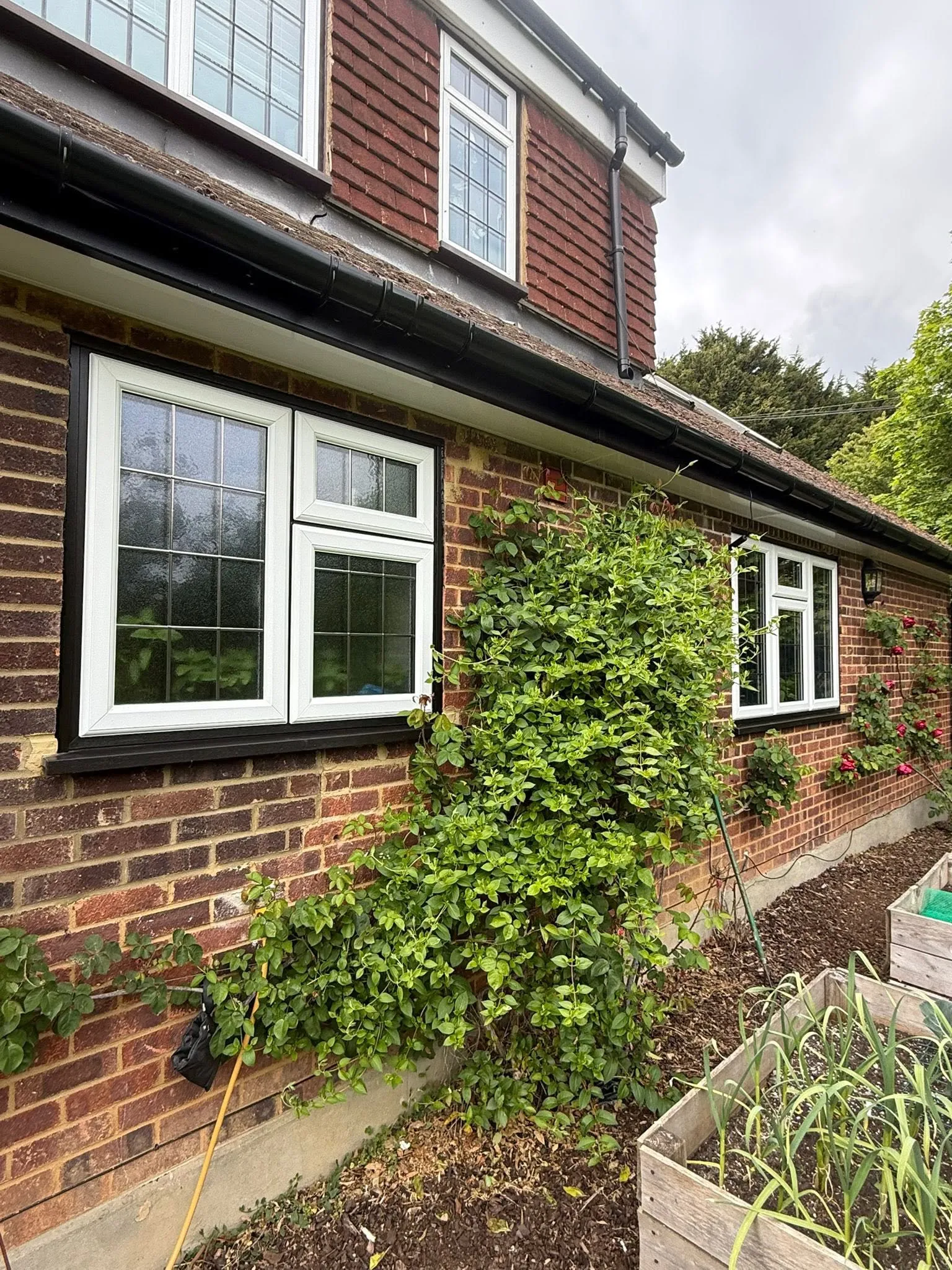 White leaded casement windows with black rooftrim on a brick and tile-hung house