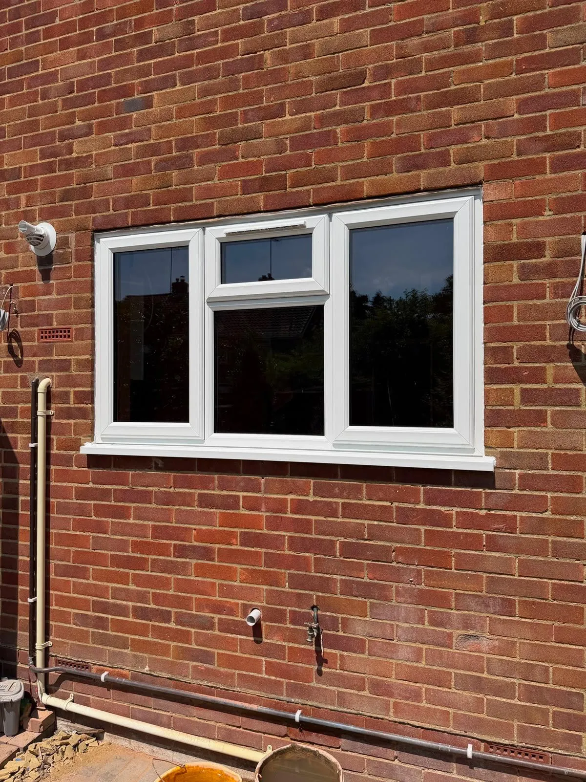 White double glazed casement window with a top opening vent in a brick wall
