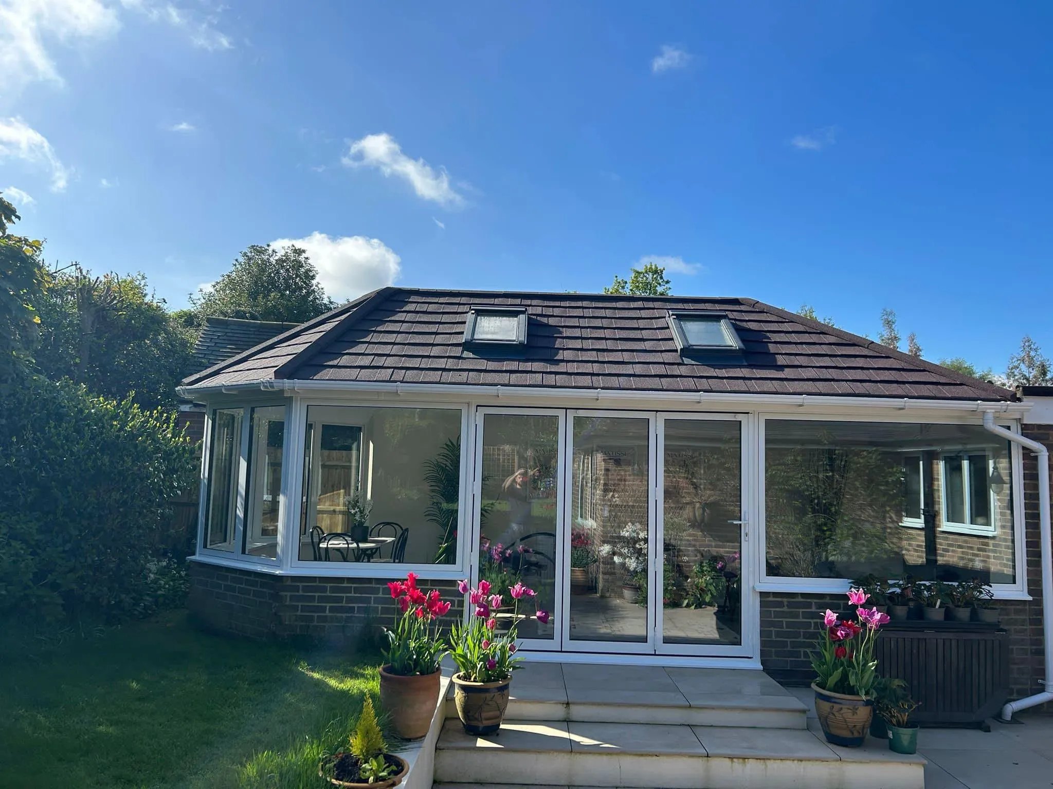 White conservatory with a dark tiled warm roof and two rooflights