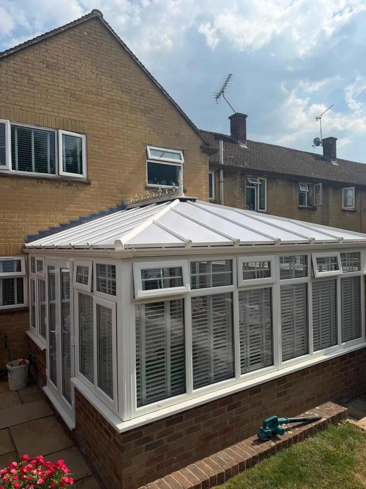 White conservatory with a solid tiled roof looking onto a garden