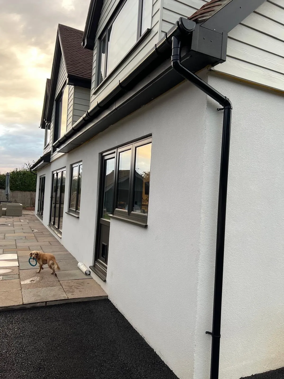 Single storey glazed extension wrapping around a rendered house