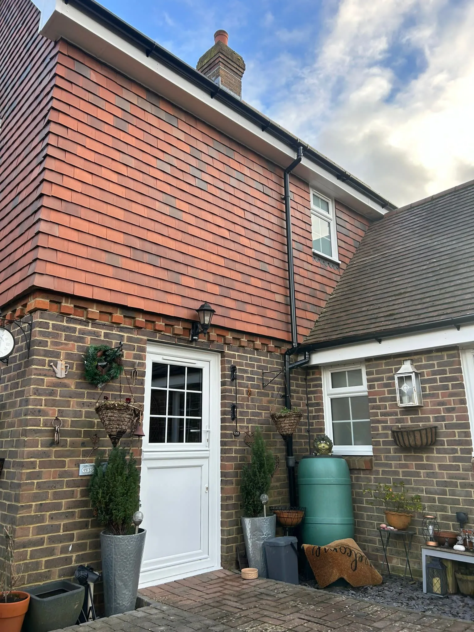 White half-glazed uPVC back door with Georgian bars on a brick and tile-hung cottage